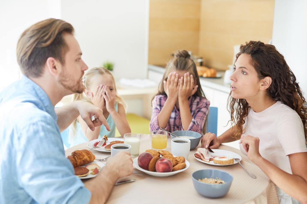 Parents having an argument at the breakfast table. Children visibly upset. 