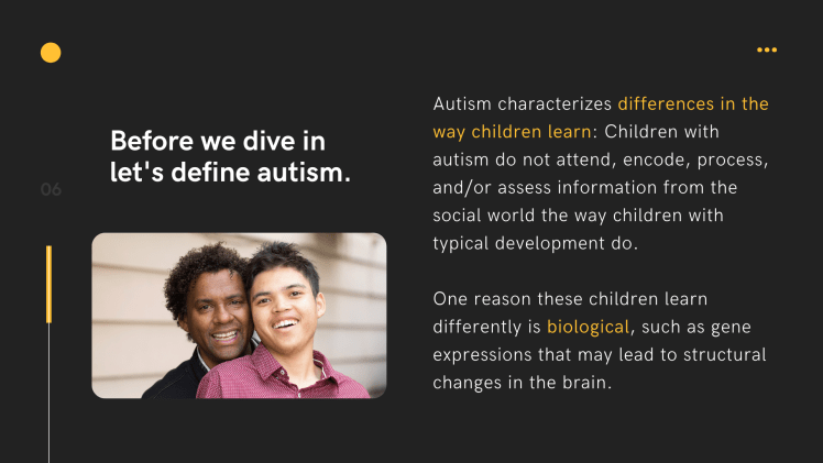 An image of a male adult wearing a black jacket, smiling and standing behind a young male who is also smiling and is wearing a red shirt.